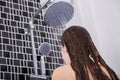 Woman is washing her hair and face by rain shower, rear view Royalty Free Stock Photo