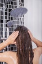 Woman is washing her hair and face by rain shower, rear view Royalty Free Stock Photo