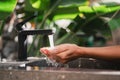 Woman washing her hands with pouring water from tap at stone sink in outdoor bathroom with tropical leaves Royalty Free Stock Photo