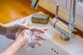 A woman is washing her hands with soap at the kitchen sink. Royalty Free Stock Photo