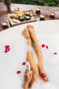 Woman washing legs in bath tub with foam bubbles and use natural loofah sponge Royalty Free Stock Photo