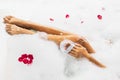 Woman washing legs in bath tub with foam bubbles and use natural loofah sponge Royalty Free Stock Photo