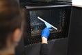 Woman washing the oven. Process of cleaning oven glass with water squeegee. Royalty Free Stock Photo