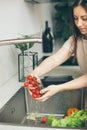 A woman washing vegetables in the kitchen sink. Side view. Royalty Free Stock Photo