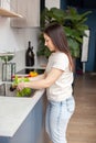 A woman washing vegetables in the kitchen sink. Side view. Royalty Free Stock Photo