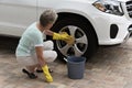 Woman washing the wheel of a white saloon car Royalty Free Stock Photo