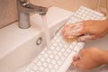Woman washing white computer keyboard with a sponge with foam.