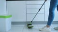 Woman washing white kitchen floor with special swob, cleaning service, close-up