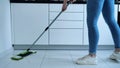 Woman washing white kitchen floor with special swob, cleaning service, close-up