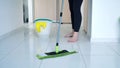 Woman washing white kitchen floor with special swob, cleaning service, close-up