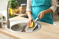 Woman washing wooden board in kitchen sink Royalty Free Stock Photo