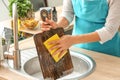 Woman washing wooden board in kitchen sink Royalty Free Stock Photo