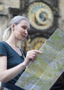 Woman watches the map of the city on background of historical medieval astronomical Clock on the Old Town Hall in Prague, Czech Re