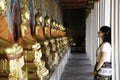 Woman watching aligned golden buddha statues in the Emerald Temple at Bangkok