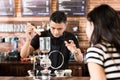 Woman watching barista preparing drip coffee in cafe