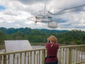 Woman watching the installation of Arecibo observatory with the help of Old Binoculars. Puerto Rico, USA