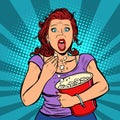 Woman watching a scary movie and eating popcorn