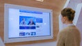 Woman watching TV news on interactive display wall