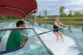 Woman water skiing holding bar protruding from boat