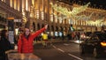 Woman waves to stop a London Taxi Cab in the city - LONDON, ENGLAND - DECEMBER 15, 2018