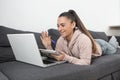 Woman waving at the camera on her laptop while taking notes in a notebook Royalty Free Stock Photo