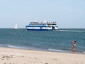 Woman waving goodbye to passengers on ferryboat leaving harbour of West Frisian island Vlieland, Netherlands Royalty Free Stock Photo