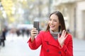 Woman waving in a video call in the street in winter