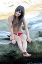Woman wear bikini sitting on sea rocks