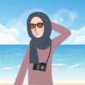 Woman wear hijab and glasses casual in beach while bring camera