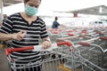Woman wear mask,using spraying alcohol antiseptic,disinfecting spray,cleaning on shopping cart,trolley handle,protection during Royalty Free Stock Photo