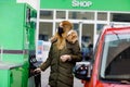 Woman wear medical mask at self-service gas station, hold fuel nozzle, refuel the car with petrol during corona virus Royalty Free Stock Photo