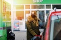 Woman wear medical mask at self-service gas station, hold fuel nozzle, refuel the car with petrol during corona virus Royalty Free Stock Photo