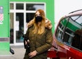 Woman wear medical mask at self-service gas station, hold fuel nozzle, refuel the car with petrol during corona virus Royalty Free Stock Photo