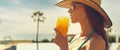 Woman wear straw hat drinks orange juice relaxing near pool Royalty Free Stock Photo