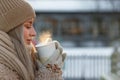 Woman wear white mittens holding steaming white cup of hot coffee or tea in cold winter sunny day Royalty Free Stock Photo