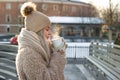 Woman wear white mittens holding steaming white cup of hot coffee or tea in cold winter sunny day Royalty Free Stock Photo