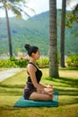 Woman wearing active wear doing yoga practice meditating in park nature, lotus position. Meditation in sunny day, inner balance Royalty Free Stock Photo