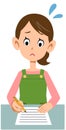 A woman wearing an apron to fill out documents with a troubled expression