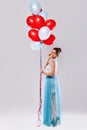 Woman wearing beautiful dress with a lot of colorful balloons