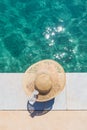 Woman wearing big summer sun hat relaxing on pier by clear turquoise sea. Royalty Free Stock Photo