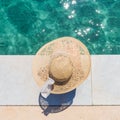 Woman wearing big summer sun hat relaxing on pier by clear turquoise sea. Royalty Free Stock Photo