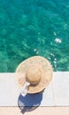 Woman wearing big summer sun hat relaxing on pier by clear turquoise sea. Royalty Free Stock Photo