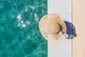 Woman wearing big summer sun hat relaxing on pier by clear turquoise sea. Royalty Free Stock Photo