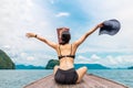 Woman wearing bikini sitting on the boat with hands up and holding beachhat. Royalty Free Stock Photo