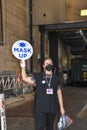 A woman wearing a black face mask is holding a round sign that says mask up outside a Broadway theater