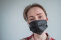 Woman wearing black medical face mask, looking at camera - quarantine concept