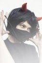 Woman wearing a black medical mask and a wig with red horns Royalty Free Stock Photo