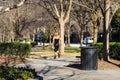 A woman wearing black pants and a black tank top walking in the park surrounded by bare winter trees, lush green plants Royalty Free Stock Photo