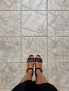 woman wearing black sandals standing on stone tiled floor