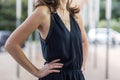 Woman wearing a black summer dress outdoors on a neutral city background